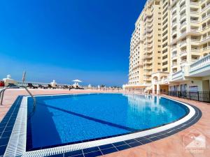 a swimming pool in front of a large building at 1BR Getaway in RAK l Balcony , Pool and Gym Access in Ras al Khaimah