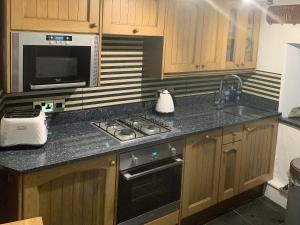 a kitchen with a stove and a sink and a microwave at Fisherman's Cottage in Plymouth