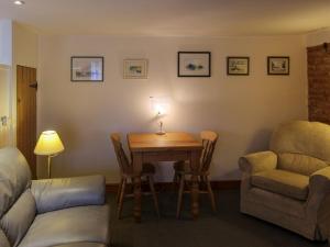 a room with a table and a chair and a couch at Hollyhocks Cottage in Docking