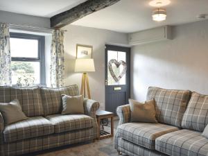 a living room with two couches and a heart window at Toms Cottage in Melmerby