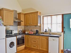 a kitchen with wooden cabinets and a washer and dryer at Rose Cottage - 30502 in West Firle