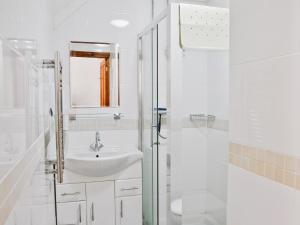 a white bathroom with a sink and a shower at Rose Cottage - 30502 in West Firle +3 photos