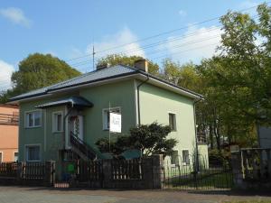 a green and white house with a black fence at Villa Karo in Łeba