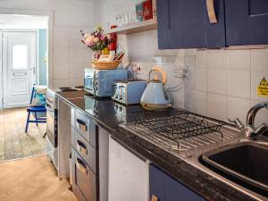 a kitchen with a stove top oven next to a sink at Seaglass Chalet - Uk47636 in Mundesley