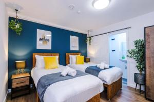 two beds in a room with blue walls at The Definition Apartment in the Northern Quarter by Rest&Recharge in Manchester +58 photos