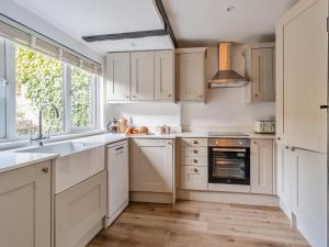 a kitchen with white cabinets and a sink and a window at Darla Cottage in Thornton Dale