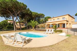 a swimming pool with chairs and a house at Villa Roselles in Lloret de Mar
