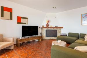 a living room with couches and a tv and a fireplace at Villa Roselles in Lloret de Mar