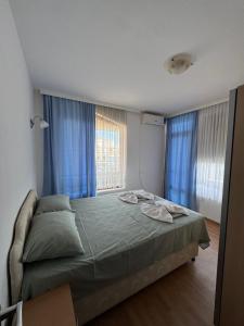 a bedroom with a large bed with blue curtains at VP Palazzo Nesebar in Nesebar