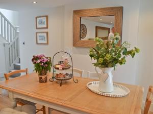 a table with a vase of flowers and a mirror at Donadea Cottage in Caerwys