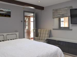 a bedroom with a white bed and a chair at The Milking Parlour - Uk30866 in St Bees +5 photos