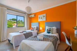 two beds in a room with an orange wall at Vila da Encosta - Private - Heated swimming pool - By bedzy in Albufeira +51 photos