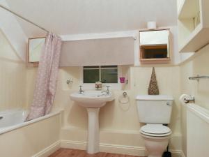 a bathroom with a toilet and a sink at Sweet Pea Cottage in Heacham +2 photos