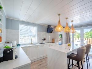 a kitchen with white cabinets and a kitchen island with chairs at Three Sandbanks in Benllech