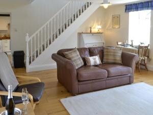 a living room with a brown couch and stairs at Dolly's Cottage in Ovingham