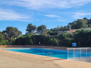 a swimming pool with blue water and trees in the background at Mas Flora in La Croix-Valmer