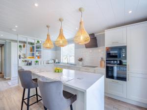 a kitchen with white cabinets and a island with chairs at Three Sandbanks in Benllech +22 photos