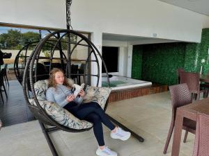a woman sitting in a chair reading a book at ApartDamani - short rental apartments in Foz do Iguaçu