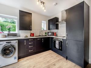 a kitchen with black cabinets and a washer and dryer at Riviera Cottages in Sewerby