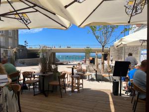 a patio with people sitting at tables and umbrellas at Le Studio Romie in Le Portel