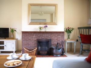 a living room with a brick fireplace with a mirror at Dulcie Cottage in Benson