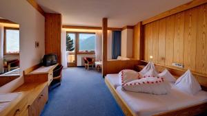 ティローロにあるHotel Tirolのベッドとテレビが備わるホテルルームです。