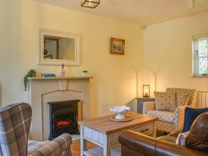 a living room with a fireplace and a couch at Cosy Cottage in Holker