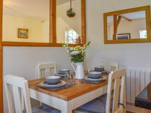 a dining room table with a vase of flowers on it at Cosy Cottage in Holker