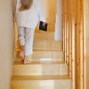 a woman walking down the stairs with a book at Sea'Ya Thoughtful Stays - Villas in Cascais