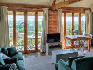 ein Wohnzimmer mit einer Couch und einem Tisch mit einem Fernseher in der Unterkunft Homer's Cottage in Cucklington