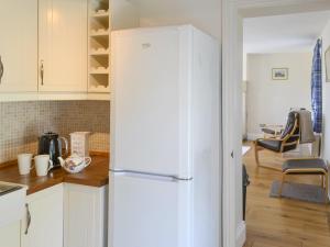 a kitchen with a white refrigerator in a kitchen at Dolly's Cottage in Ovingham