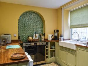 a kitchen with a stove and a green tile wall at Home Cottage in Hovingham