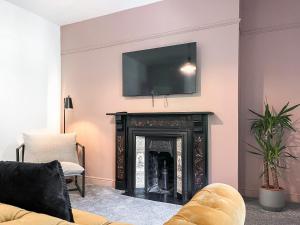 a living room with a fireplace with a tv on the wall at Pavilion Mews in Buxton
