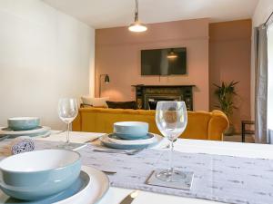 a table with plates and glasses on it with a living room at Pavilion Mews in Buxton +9 photos