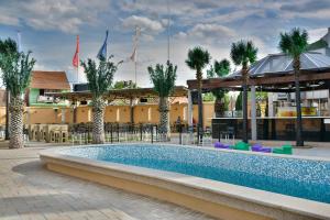 einen Pool in einem Resort mit Palmen und einem Gebäude in der Unterkunft Hotel Bella Nella in Leskovac
