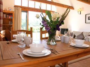 ein Holztisch mit einer Vase mit Blumen darauf in der Unterkunft The Barn At Fishponds in Brook