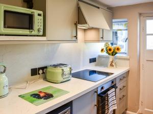 a kitchen with a stove and a microwave at Wallthwaite Cottage in Threlkeld