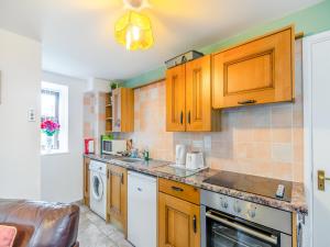 eine Küche mit Holzschränken und einem Geschirrspüler in der Unterkunft The Cottage - Uk43952 in Boosbeck