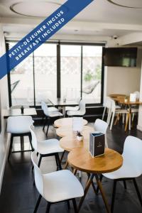 a restaurant with tables and white chairs and windows at Hôtel Les Voiles in Toulon