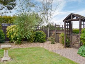 a garden with a wooden fence and a wooden pergola at Sunflower Holiday Cottage in Alford +4 photos