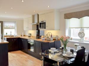 een keuken met witte kasten en een tafel met stoelen bij Ingram Cottage in Bamburgh
