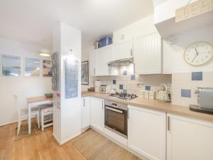 een keuken met witte kasten en een klok aan de muur bij Stonehanger 2 - Cottage in Salcombe