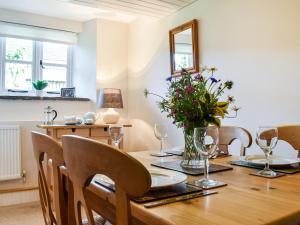 a dining room with a wooden table with flowers on it at Fox Cover Cottage in Great Edston