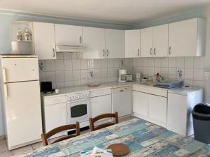 a kitchen with white cabinets and a white refrigerator at An Distro Pesketa in Penmarch