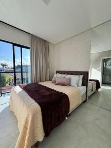 een slaapkamer met een groot bed en een groot raam bij Casa Nova - Moderna | 700m praia | 8 min parque in São Lídio +30 foto's