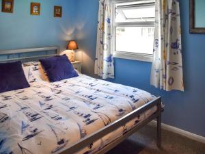 a bedroom with a bed with blue walls and a window at Seaglass Chalet - Uk47636 in Mundesley