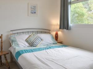 ein Schlafzimmer mit einem Bett mit weißen Laken und einem Fenster in der Unterkunft Chalet 6 - Uk12566 in Mount Hawke