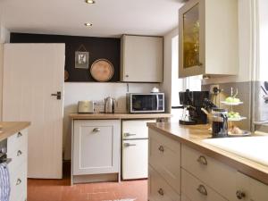 een keuken met witte kasten en een magnetron bij Cenwulf Cottage in Winchcombe