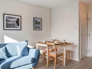Una sala de estar con una mesa y un sofá azul. en Hillside At Bowness, en Windermere