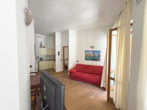 a living room with a red couch and a kitchen at Bilocale sulle piste da sci in Pila